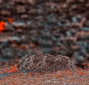 Rugged volcanic rock formation with glowing embers and dry grass in a moody landscape HD wallpaper