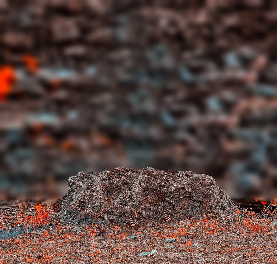 Rugged volcanic rock formation with glowing embers and dry grass in a moody landscape HD wallpaper