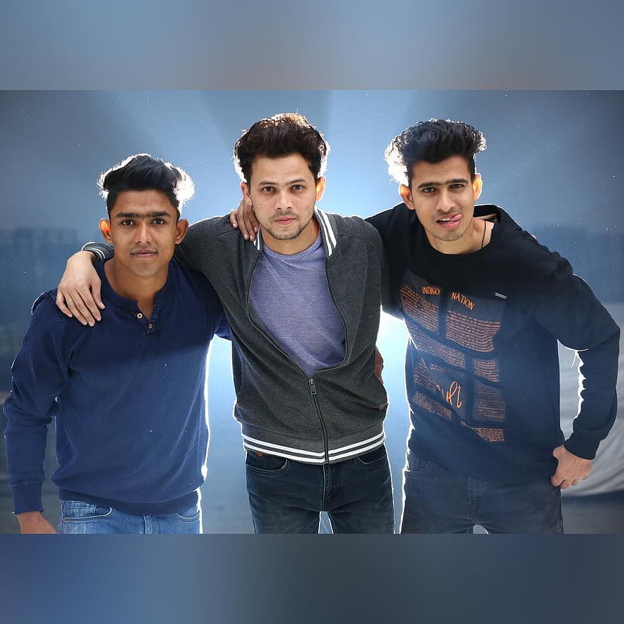Three Young Men Standing Together in Casual Streetwear Against a Blue Sky HD phone wallpaper