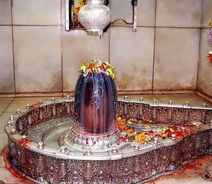 Mahakaleshwar Jyotirlinga shrine with water pouring from silver pot and floral offerings HD wallpaper