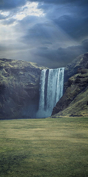 Majestic Waterfall Cascading Through Dramatic Cliffs Under Stormy Skies HD phone wallpaper