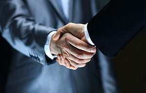 Professional Business Handshake Between Two Executives in Formal Suits HD wallpaper