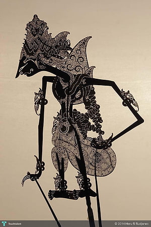 Intricate Black Wayang Kulit Shadow Puppet with Ornate Carved Details on Beige Background HD phone wallpaper
