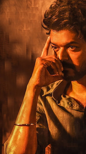 Thalapathy Vijay in a moody contemplative portrait with warm amber lighting and textured background HD phone wallpaper