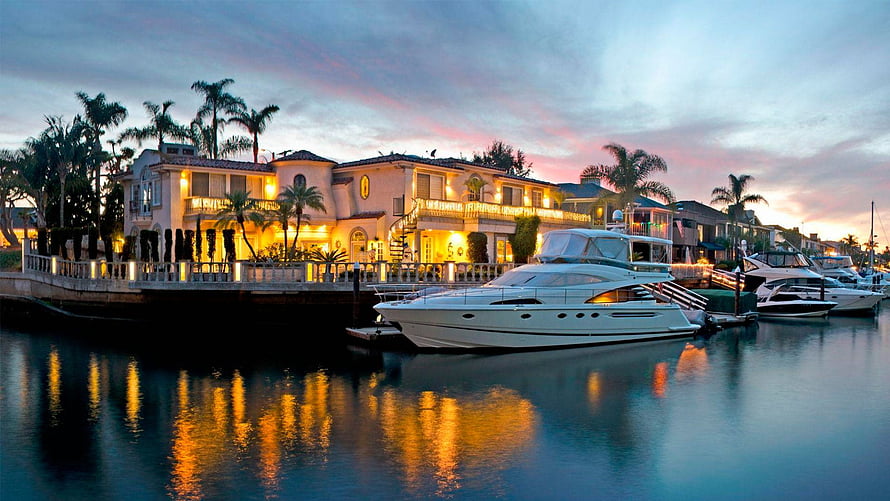 Luxury Waterfront Mansion at Dusk with Yacht and Palm Trees HD wallpaper