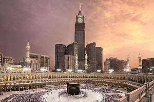 Makkah Royal Clock Tower Hotel and the Grand Mosque at sunset with pilgrims gathered around the Kaaba HD wallpaper