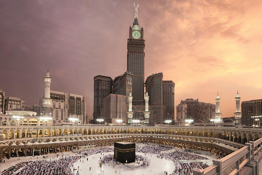 Makkah Royal Clock Tower Hotel and the Grand Mosque at sunset with pilgrims gathered around the Kaaba HD wallpaper