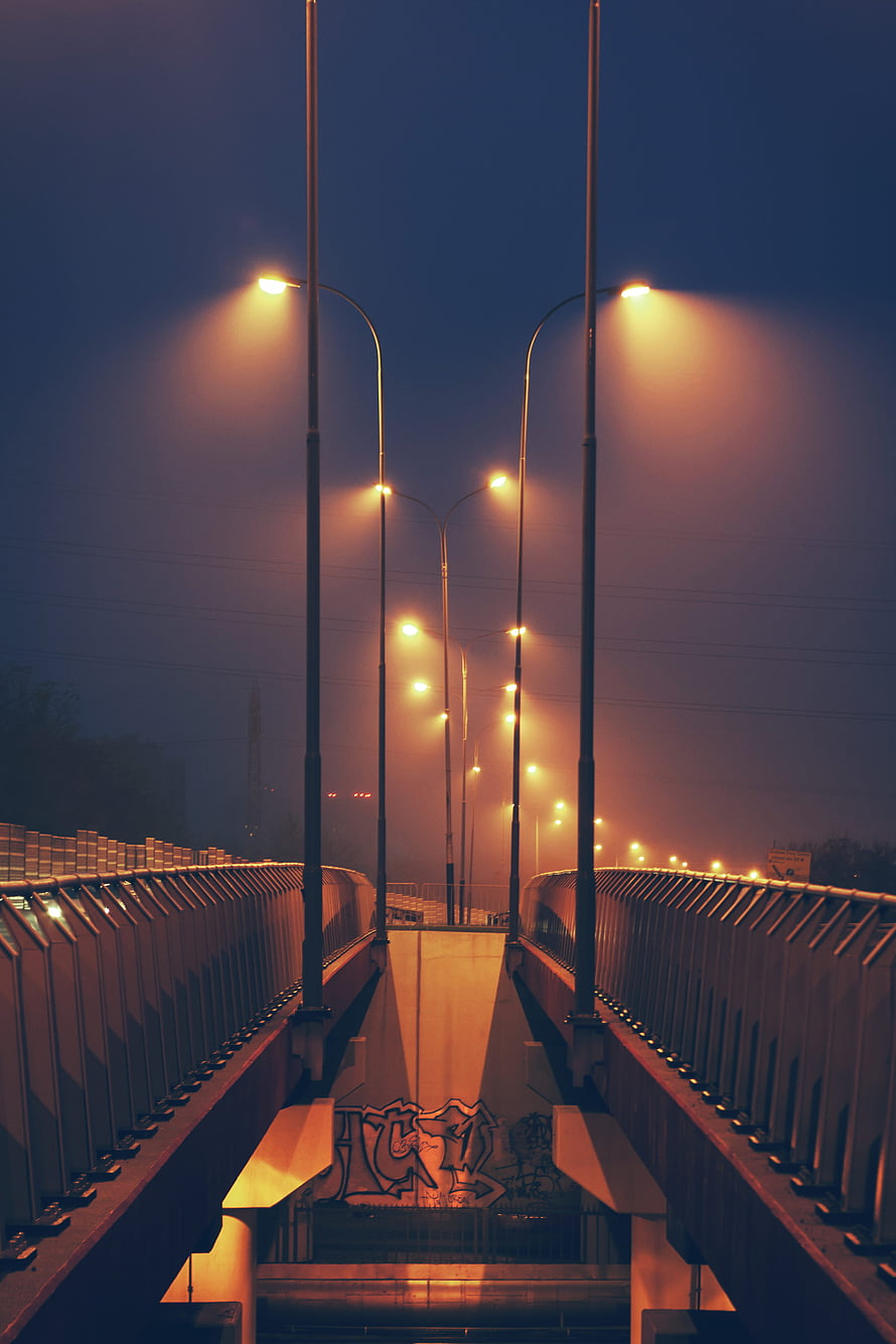 Symmetrical Streetlights on a Foggy Bridge at Night with Warm Orange Glow HD phone wallpaper