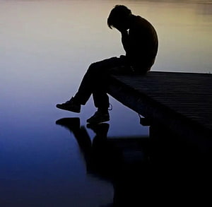 Silhouette of a person sitting alone on a dock at dusk with a calm water reflection HD wallpaper