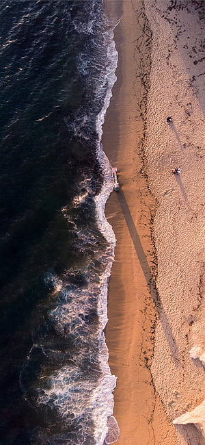 Aerial View of Ocean Waves Meeting a Sandy Beach at Golden Hour HD phone wallpaper