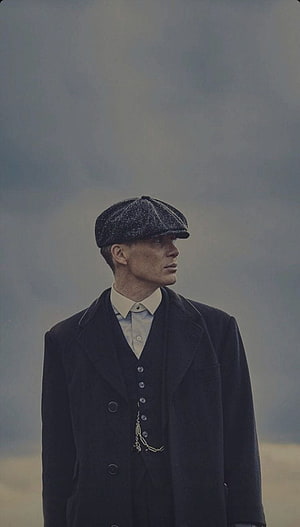 Tommy Shelby in Peaky Blinders Flat Cap and Dark Overcoat Against Misty Sky HD phone wallpaper