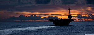 Silhouetted Aircraft Carrier on the Open Ocean During a Dramatic Sunset HD wallpaper