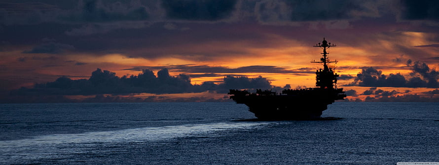 Silhouetted Aircraft Carrier on the Open Ocean During a Dramatic Sunset HD wallpaper