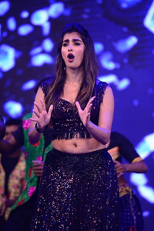 Pooja Hegde performing on stage in a sparkling black sequined crop top and skirt under blue concert lighting HD phone wallpaper