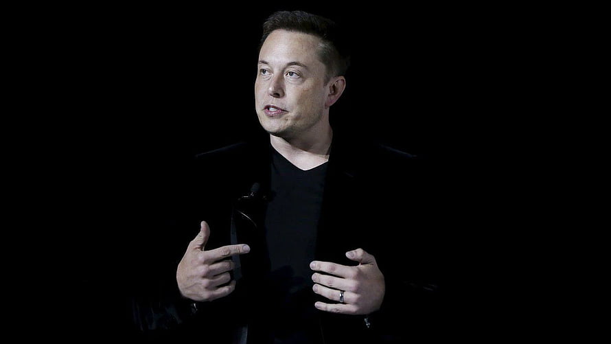 Elon Musk Speaking on Stage in Black Attire Against Dark Background HD wallpaper