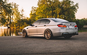 Silver BMW M5 F10 Sedan with Bronze Wheels Parked by a Lake at Sunset HD wallpaper