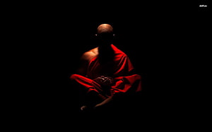 Silhouette of a Buddhist monk in red robes meditating in darkness HD wallpaper