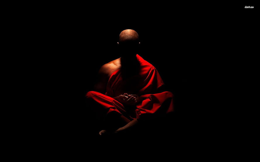 Silhouette of a Buddhist monk in red robes meditating in darkness HD wallpaper