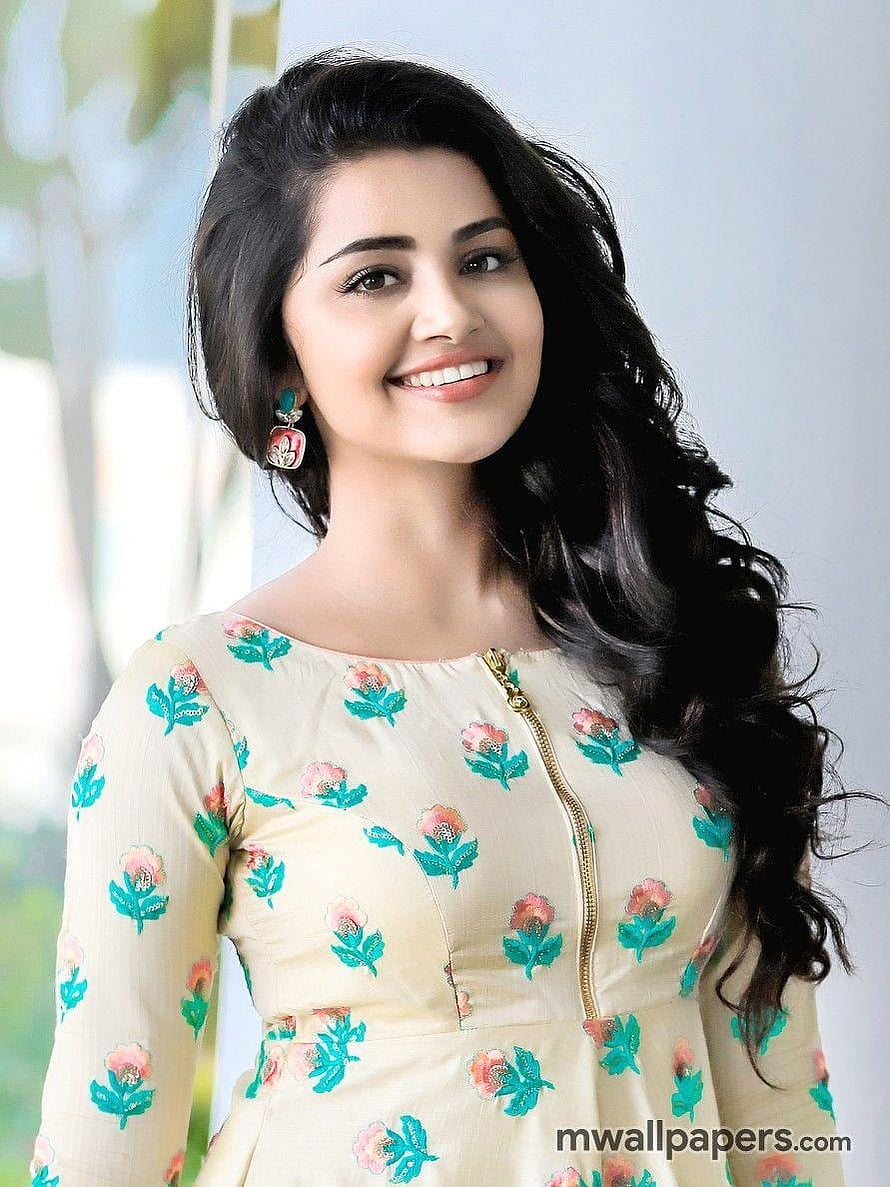 Anupama Parameswaran smiling portrait in a cream floral dress with long wavy hair and statement earrings HD phone wallpaper