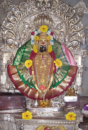 Ornate Mahalaxmi Deity Adorned With Marigold Garlands And Silver Temple Backdrop HD phone wallpaper