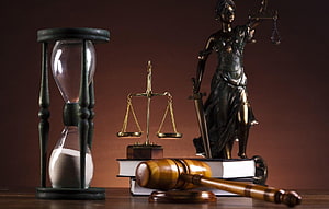 Lady Justice statue with scales, gavel, law books, and hourglass on a dark background HD wallpaper