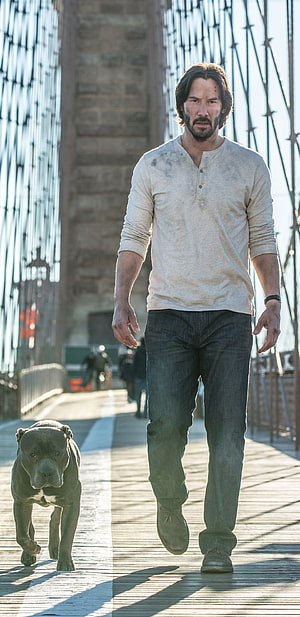 Keanu Reeves as John Wick walking a pit bull on a wooden bridge in a gritty urban setting HD phone wallpaper