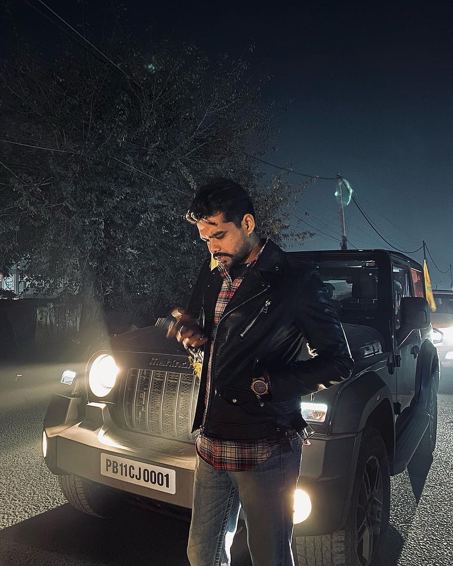 Arjan Dhillon posing in a black leather jacket beside a Maruti Gypsy at night HD phone wallpaper