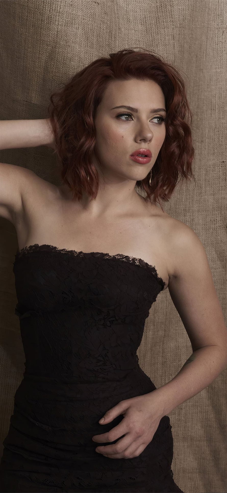 Scarlett Johansson in a black lace strapless dress with wavy red hair against a textured burlap backdrop HD phone wallpaper
