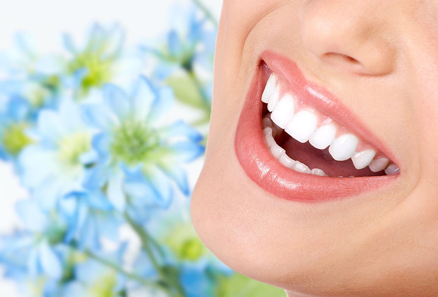 Close-up of a bright white smile with soft blue flowers in the background HD wallpaper