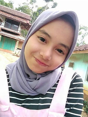 Young woman in a lavender hijab and striped shirt taking a selfie outdoors HD phone wallpaper