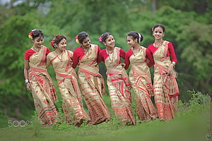 Six Women in Traditional Assamese Bihu Sarees Performing Folk Dance in a Lush Green Field HD wallpaper