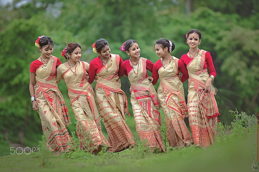 Six Women in Traditional Assamese Bihu Sarees Performing Folk Dance in a Lush Green Field HD wallpaper