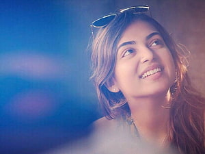 Nazriya Nazim smiling portrait with sunglasses on head against a soft blue background HD wallpaper