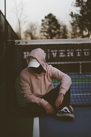 Mysterious Hooded Figure Sitting on Tennis Court Net Post HD phone wallpaper