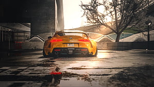 Rear View of a Yellow Toyota Supra Parked on a Wet Urban Street at Sunset HD wallpaper