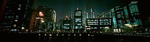 Illuminated City Skyline at Night with Waterfront Reflections and Neon Lights HD wallpaper