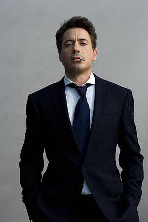 Robert Downey Jr in a dark pinstripe suit with a cigarette against a neutral grey studio backdrop HD phone wallpaper
