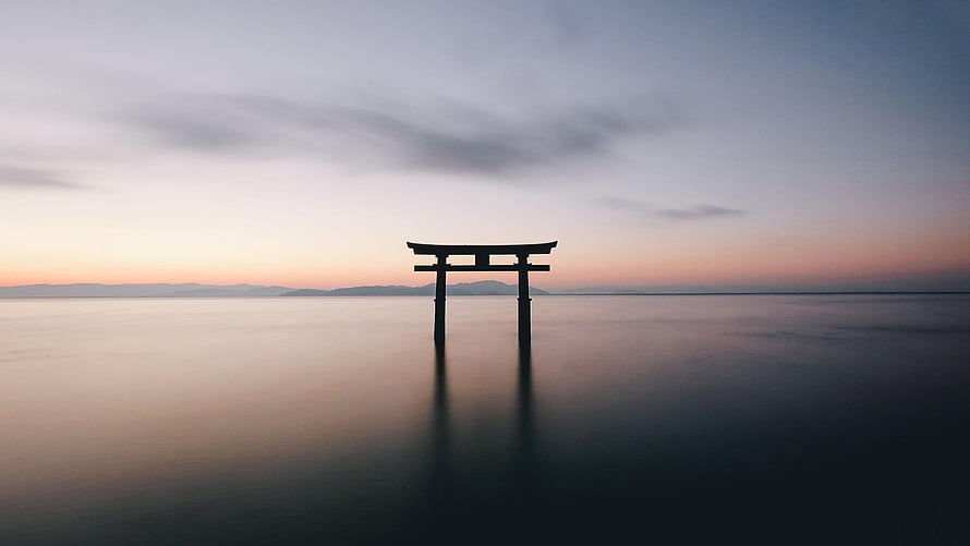 Silhouette of a Japanese Torii Gate Standing in Calm Ocean Water at Dusk HD wallpaper