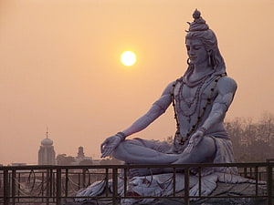 Lord Shiva Meditating at Sunrise with Temple Silhouettes in the Background HD wallpaper