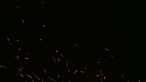 Glowing Orange Sparks and Embers Scattering Against a Deep Black Background HD wallpaper