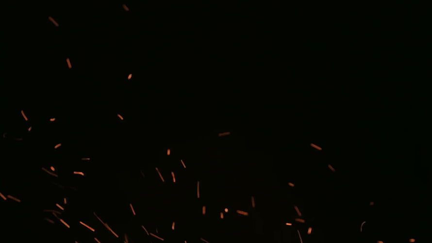 Glowing Orange Sparks and Embers Scattering Against a Deep Black Background HD wallpaper