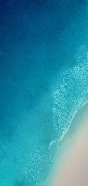 Aerial View of Turquoise Ocean Waves Lapping Against White Sandy Beach HD phone wallpaper