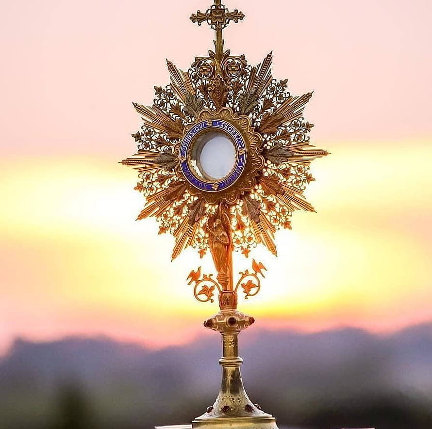 Ornate Golden Monstrance with Eucharistic Host Against a Warm Sunset Sky HD wallpaper