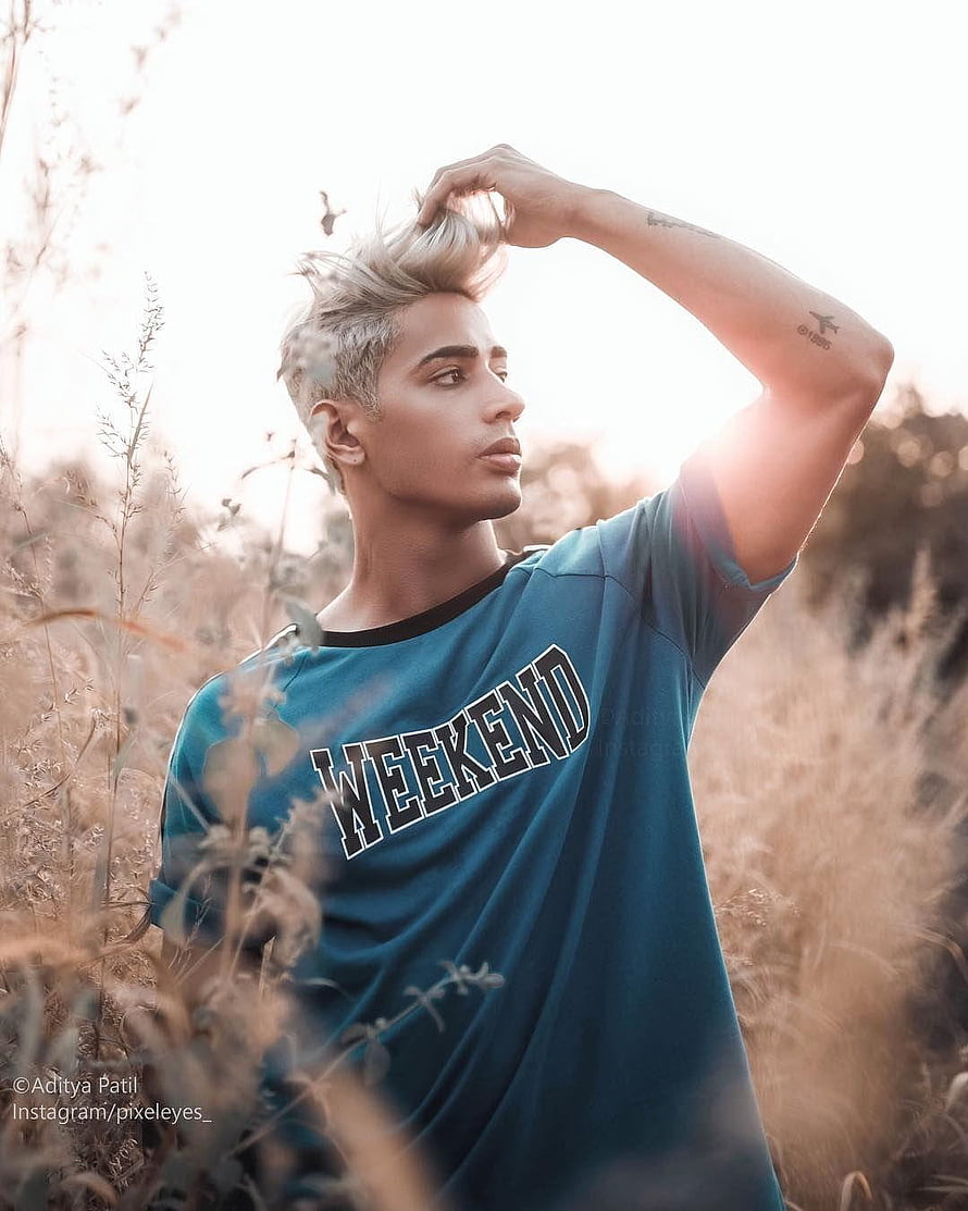 Danish Zehen in a teal Weekend t-shirt standing in a field of dry grass at golden hour HD phone wallpaper