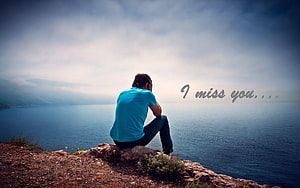 Lonely Man Sitting on Rocky Cliff Overlooking Calm Sea Under Overcast Sky HD wallpaper