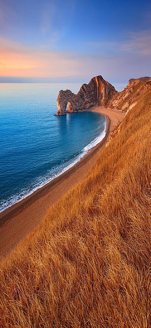 Golden Hour Coastal Cliffs and Sandy Beach with Turquoise Ocean Water HD phone wallpaper