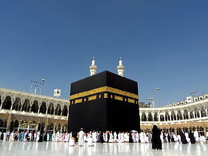The Holy Kaaba in Mecca with Pilgrims Performing Tawaf Under a Clear Blue Sky HD wallpaper