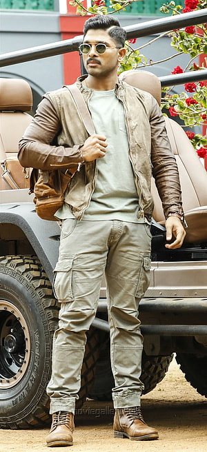 Allu Arjun in rugged cargo pants and leather jacket beside an off-road vehicle HD phone wallpaper