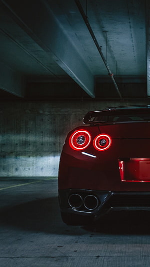 Rear View of a Red Nissan GT-R with Glowing Taillights in a Concrete Parking Garage HD phone wallpaper
