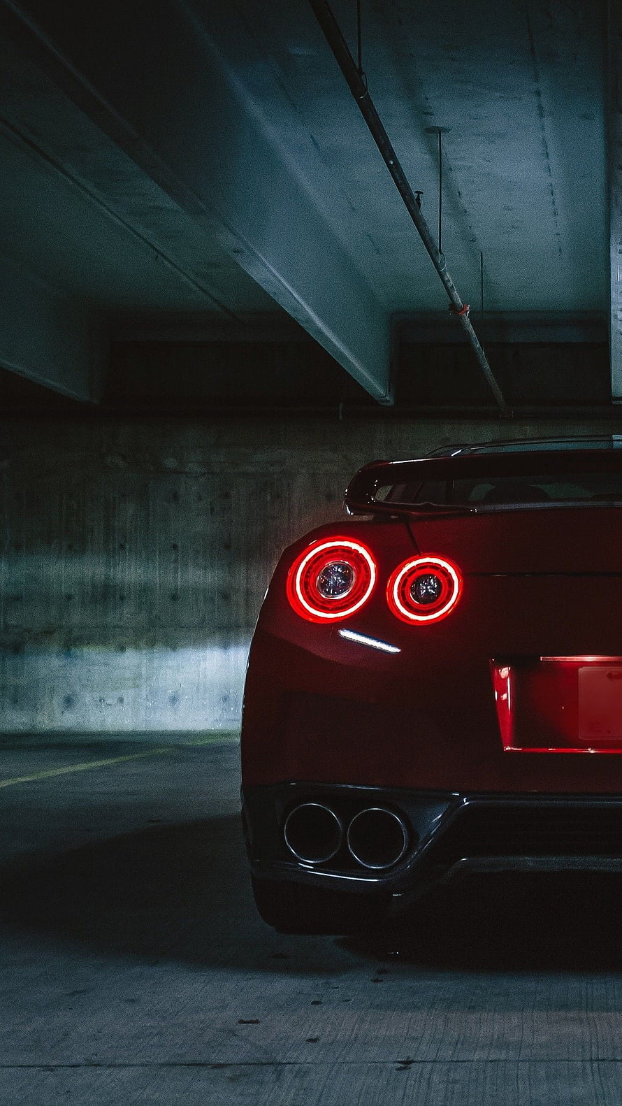 Rear View of a Red Nissan GT-R with Glowing Taillights in a Concrete Parking Garage HD phone wallpaper